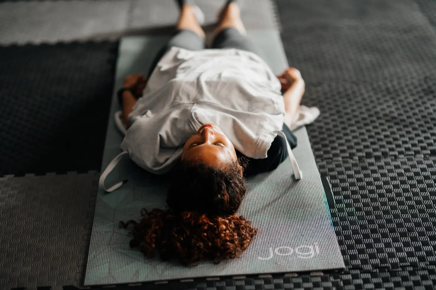 Meditation for sleep: a woman lying on her back on a yoga mat with eyes closed during a guided relaxation