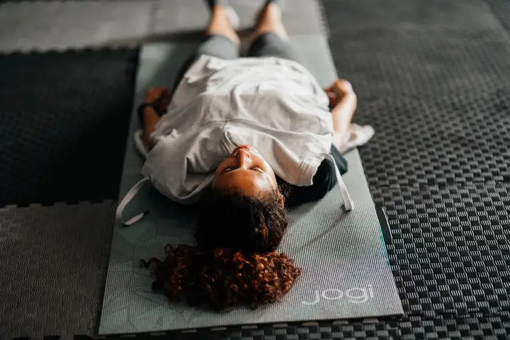 Meditation for sleep: a woman lying on her back on a yoga mat with eyes closed during a guided relaxation